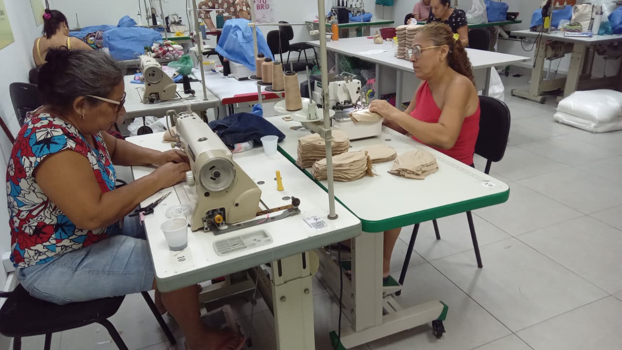 mulhers sentadas diante de máquinas de costuras